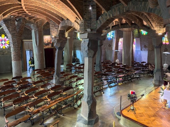 Gli interni della Cripta di Gaudì alla Colonia Guell in cui si vedono le panche, parte dell'altare e le colonne
